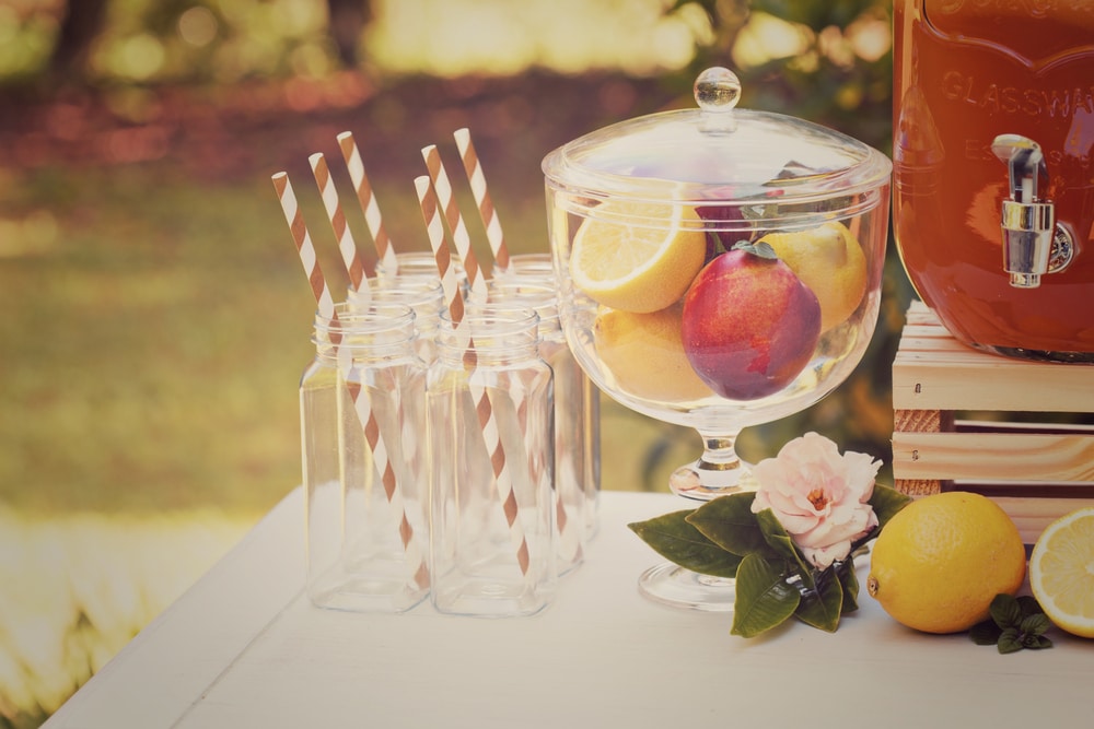 Decorative outdoor party drink station with small bottles and homemade peach lemonade