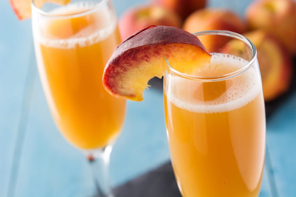 Bellini champagne cocktail in crystal glass on blue wooden table. Pretty as a Peach!