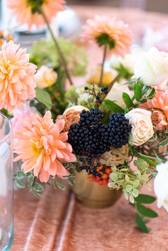 Festive banquet decor in peach color. Autumn flower bouquet chrysanthemums and eucalyptus, elderberry branch in a bouquet set on a silky peach tablecloth in a gold vase.