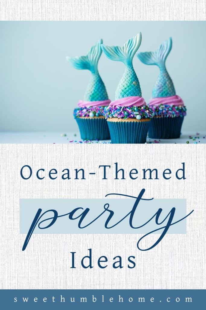 Three vanilla cupcakes with blue liners and pink and blue frosting with a candy mermaids tail on the top. Cupcakes for an ocean-themed birthday party