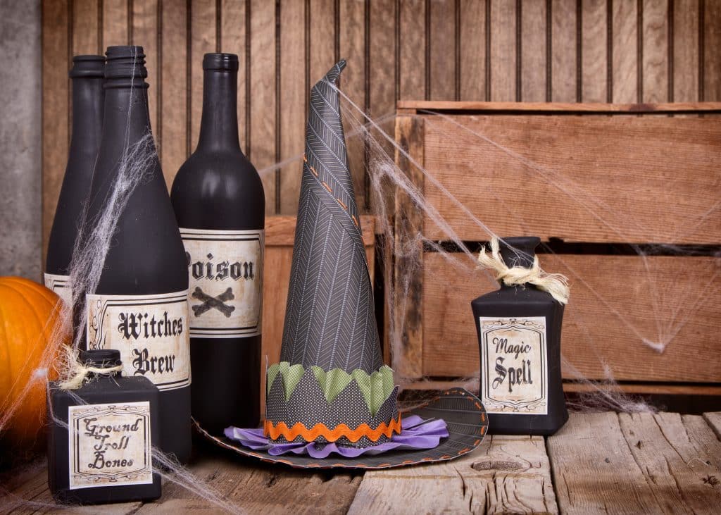 Potion bottles and witches hat with pumpkins and gourds on wooden planks.