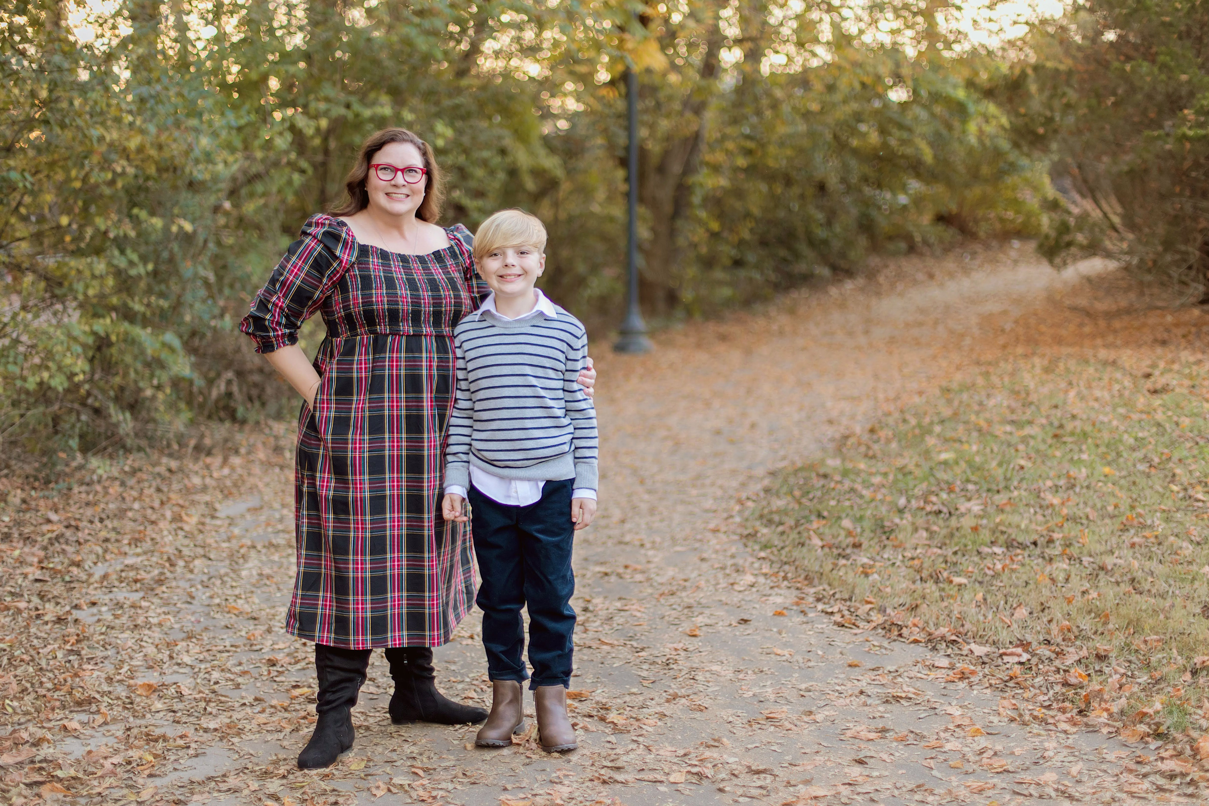 A portrait of a mother standing beside her young son outside.