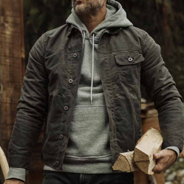 a man wearing a wool lined trucker style jacket over a pullover hoodie sweater