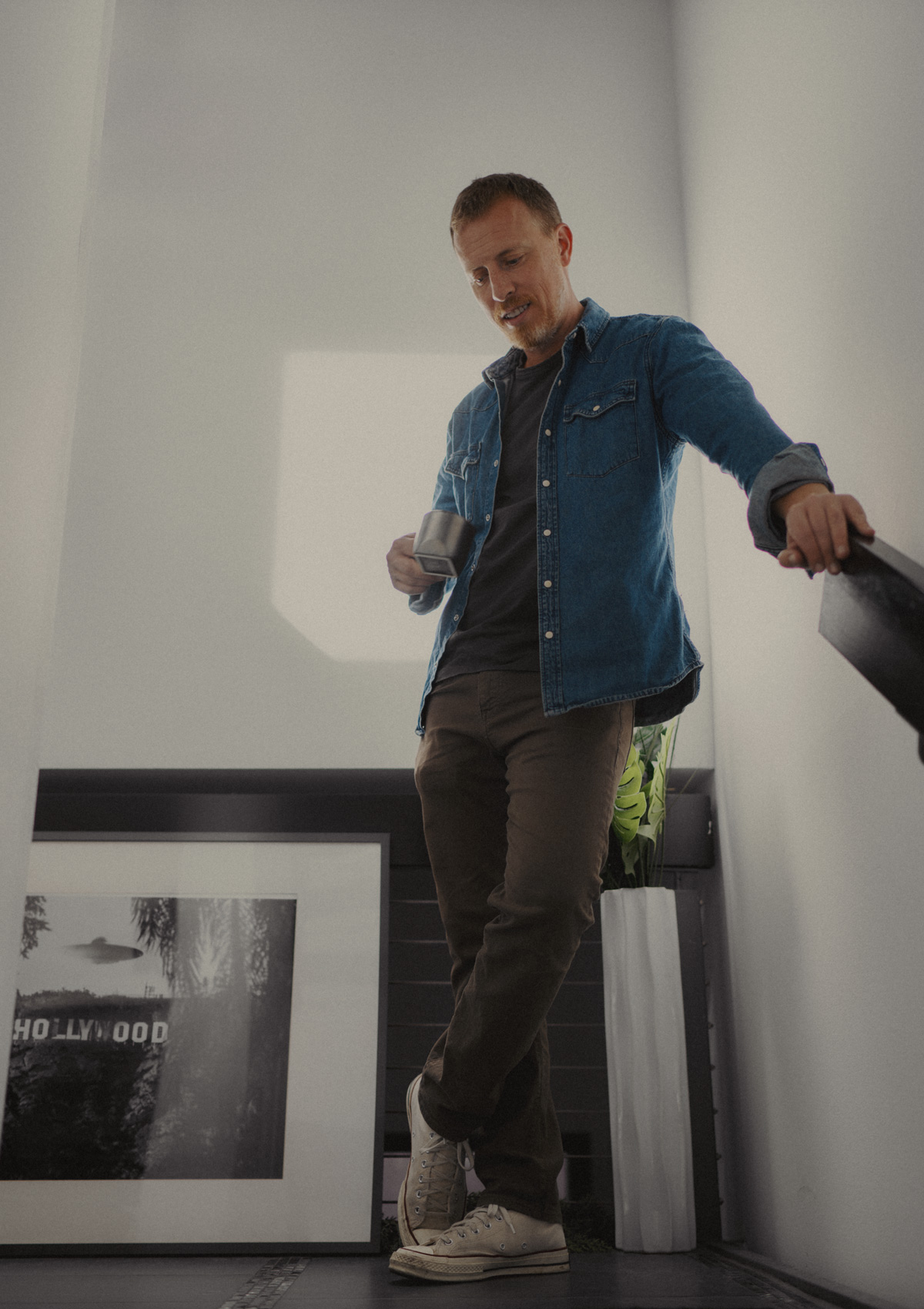 mens casual outfit with medium blue denim western shirt over a black tshirt with brown jeans and tan converse sneakers